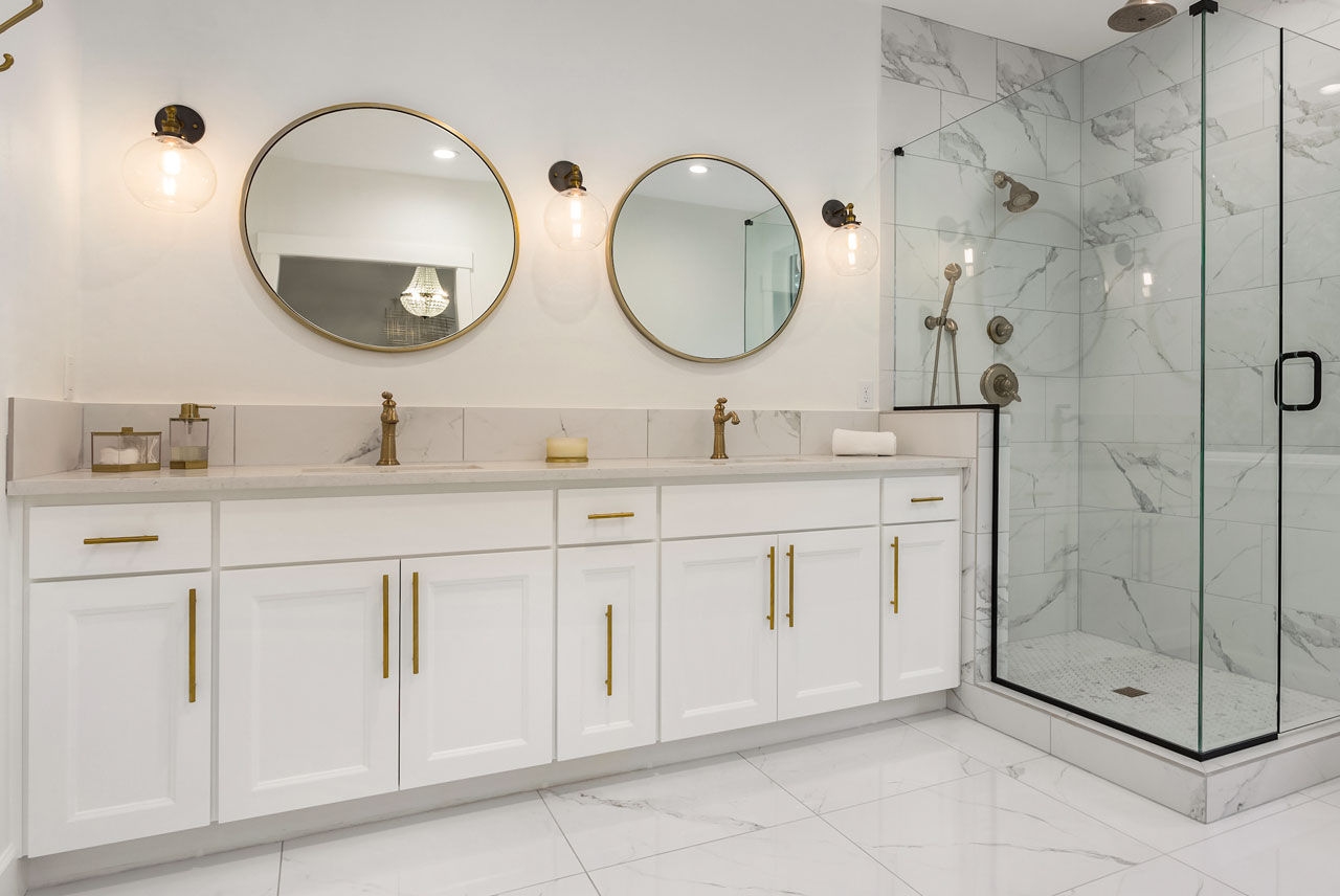 BOCA Renovations luxury bathroom with double vanity, marble shower, and gold fixtures